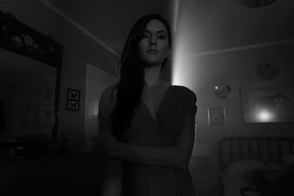 Black and white image of woman facing the camera in a dark room