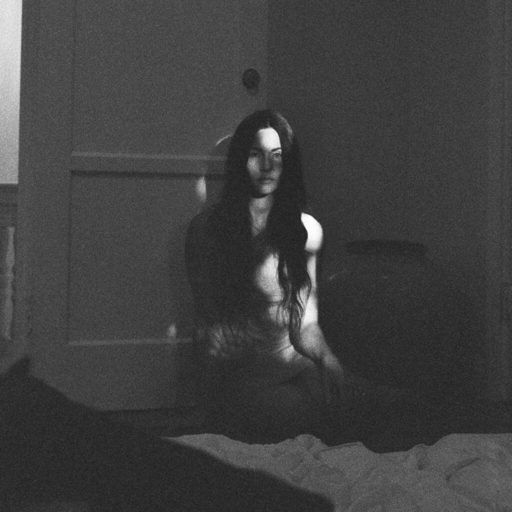 Black and white image of woman sitting in a dark room.