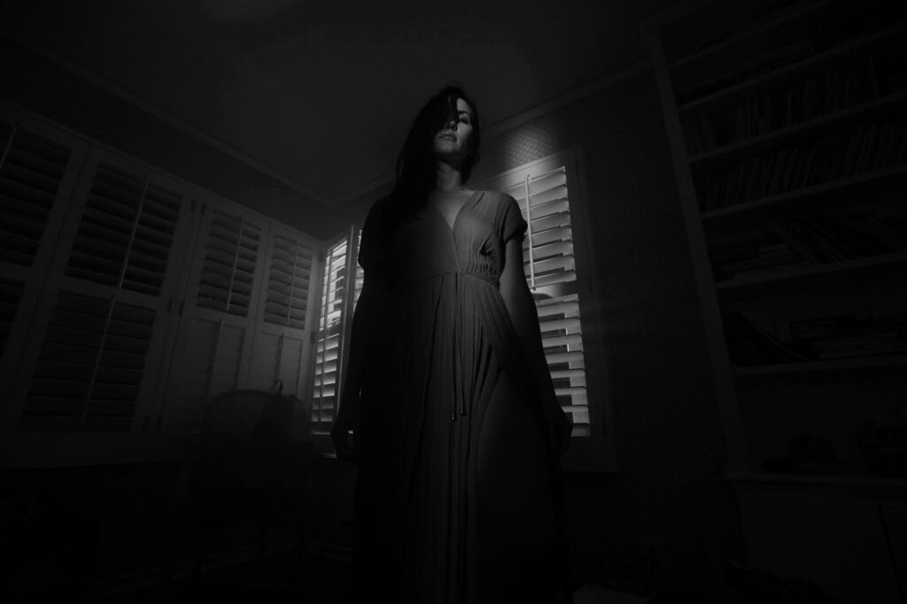 Black and white image of woman, standing in a room
