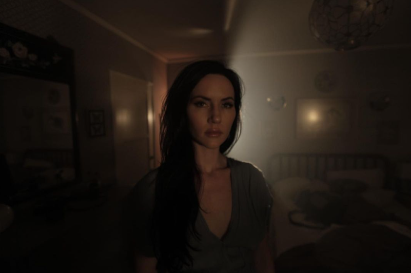 Image of woman standing in a dark room.