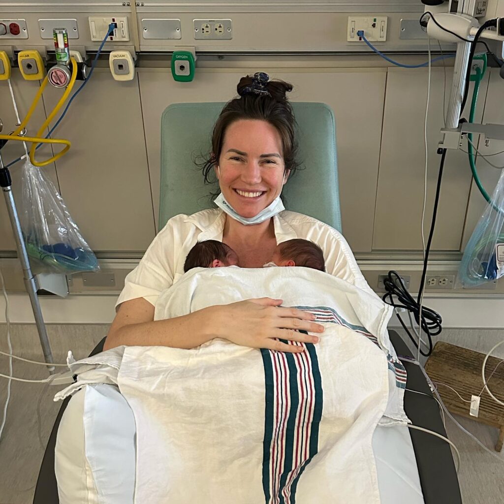 Image of woman in the hospital holding her newbord twins. 