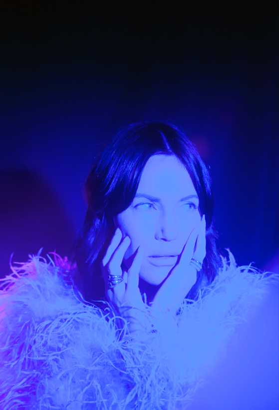 Image of woman with a feather jacket in a blue room