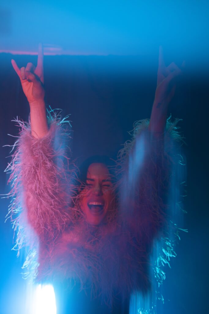 Image of woman in feather jacket, celebrating.